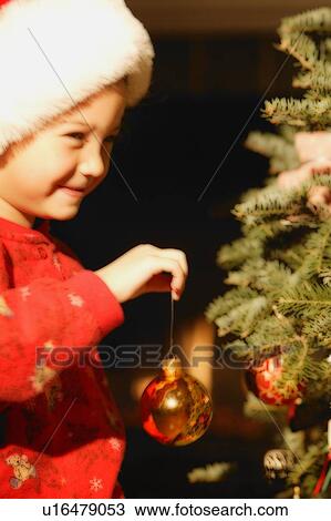 Stock Image - Girl Hanging Ornament on Christmas Tree. Fotosearch
