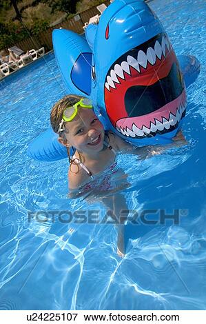 Girl playing in swimming pool with inflatable shark View Large Photo Image Stock Photo - Girl playing in swimming pool with inflatable shark. Fotosearch