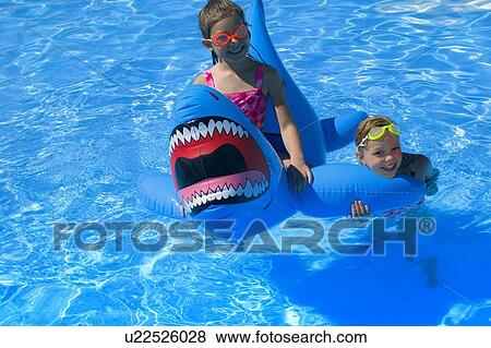 Girls playing in swimming pool with inflatable shark View Large Photo Image Stock Photo - Girls playing in swimming pool with inflatable shark. Fotosearch