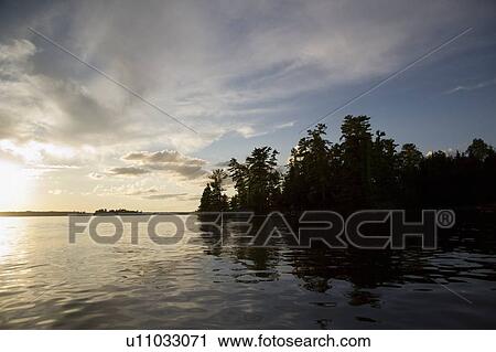 Stock Image - Lake of the Woods, Ontario, Canada; View of woods next to a lake. Fotosearch