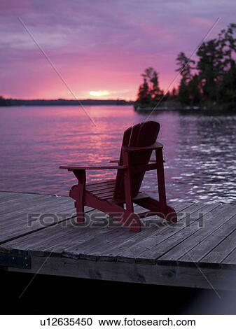 Lake of the Woods, Ontario, Canada; Empty deck chair on a pier next to a lake View Large Photo Image Stock Image - Lake of the Woods, Ontario, Canada; Empty deck chair on a pier next to a lake. Fotosearch