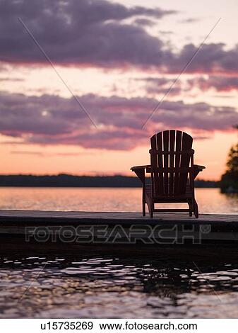 Lake of the Woods, Ontario, Canada; Empty deck chair on a pier next to a lake View Large Photo Image Stock Photo - Lake of the Woods, Ontario, Canada; Empty deck chair on a pier next to a lake. Fotosearch
