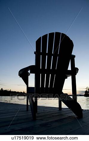 Lake of the Woods, Ontario, Canada; Empty deck chair on a pier next to a lake View Large Photo Image Stock Photo - Lake of the Woods, Ontario, Canada; Empty deck chair on a pier next to a lake. Fotosearch