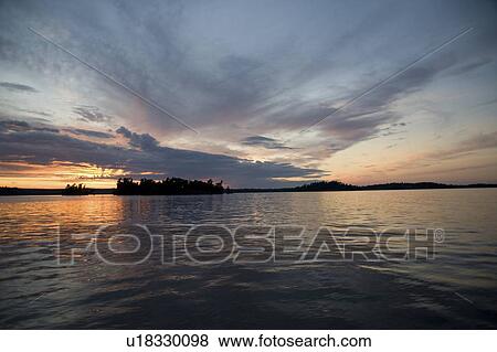 Stock Photo - Lake of the Woods, Ontario, Canada; Dramatic sunset over lake. Fotosearch