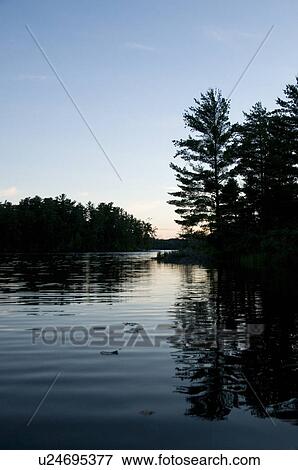 Stock Photo - Lake of the Woods, Ontario, Canada; Sunset over placid lake. Fotosearch