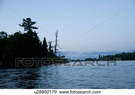 Stock Photo - Lake of the Woods, Ontario, Canada; Sunset over placid lake. Fotosearch
