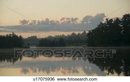 Stock Photograph - Lake of the Woods, Ontario, Canada; View across lake at sunrise. Fotosearch