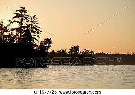 Lake of the Woods, Ontario, Canada; Majestic sunset casting glow over lake View Large Photo Image Stock Photography - Lake of the Woods, Ontario, Canada; Majestic sunset casting glow over lake. Fotosearch
