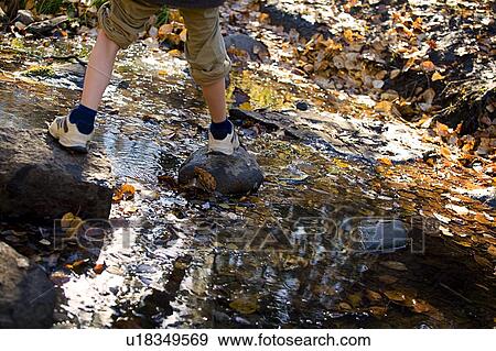Low section of boy stepping on stones View Large Photo Image Stock Photo - Low section of boy stepping on stones. Fotosearch