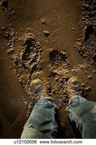 Stock Photograph - Low section of person standing in mud. Fotosearch