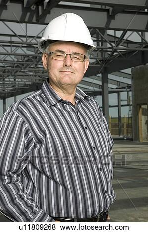 Man in hardhat in partially built building View Large Photo Image Stock Photo - Man in hardhat in partially built building. Fotosearch