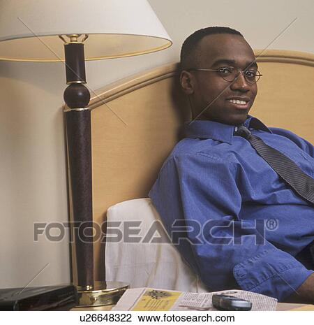 Stock Image - Man reclining on bed. Fotosearch
