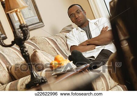 Man relaxing on sofa View Large Photo Image Stock Photograph - Man relaxing on sofa. Fotosearch