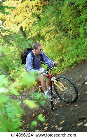Picture - Man riding trail bike in forest. Fotosearch