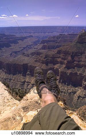 Picture - Man sitting on edge of canyon. Fotosearch