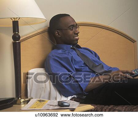 Stock Image - Man watching hotel television. Fotosearch