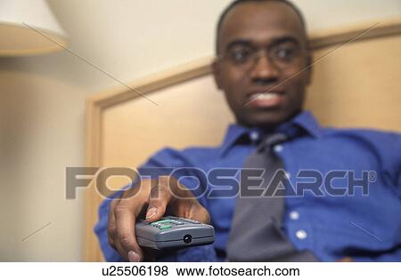 Stock Photo - Man watching television with remote. Fotosearch