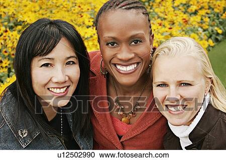 Stock Image - Multiethnic portrait of three women outdoors. Fotosearch