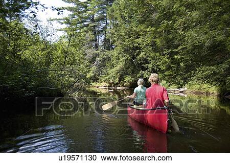 Stock Image - Muskokas, Ontario, Canada; couple canoeing down a river. Fotosearch