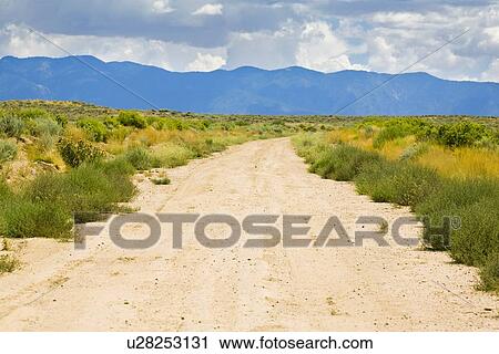 Stock Image - New Mexico, USA; Desert trail with mountains in the distance. Fotosearch