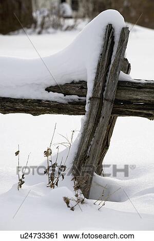 Stock Image - Old wooden fence covered in snow. Fotosearch