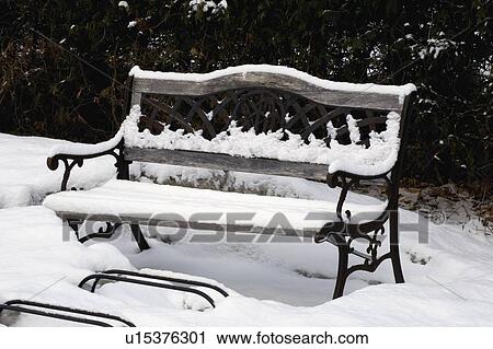 Stock Image - Park bench covered in snow. Fotosearch