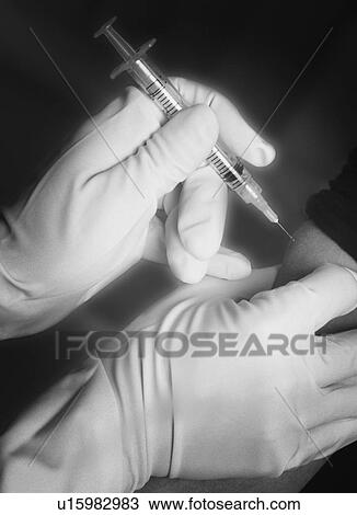Stock Image - Patient receiving injection in arm. Fotosearch