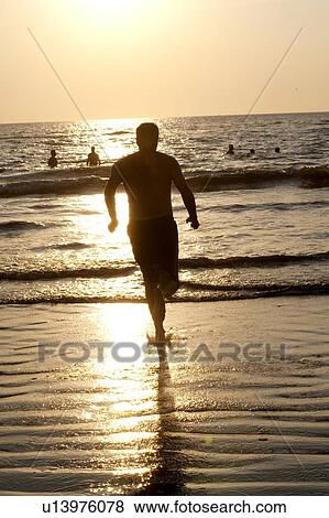 Stock Photo - Puerto Vallarta, Mexico; Man running into the water . Fotosearch