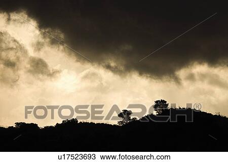 Stock Image - Ridge of a hill set against stormy sky . Fotosearch