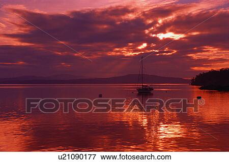 Stock Photo - Sailboat at anchor with cloudy evening. Fotosearch