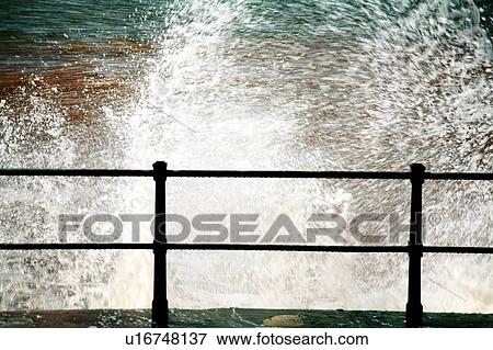 Stock Photo - Sidmouth, Devon, England, United Kingdom; Waves crashing against the seawall. Fotosearch