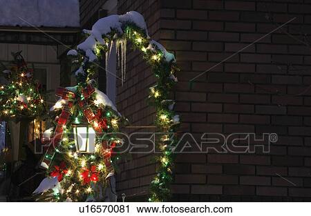 Stock Image - Snow covered Christmas decorations outside a house. Fotosearch