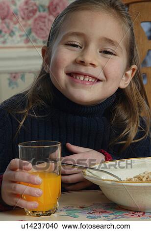 Stock Image - Young girl with food at breakfast table. Fotosearch