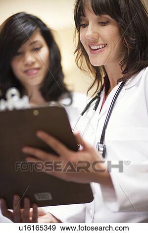 2 Female Doctors reading record smiling View Large Photo Image Stock Photo - 2 Female Doctors reading record smiling. Fotosearch