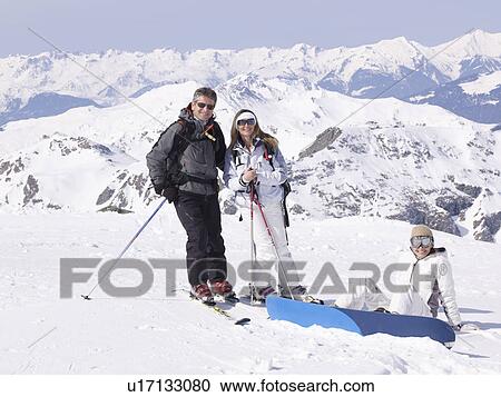 Stock Image - 3 people standing in the snow laughing. Fotosearch