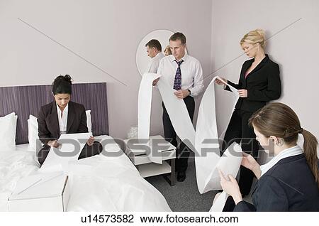 Stock Image - A business foursome read computer paper. Fotosearch
