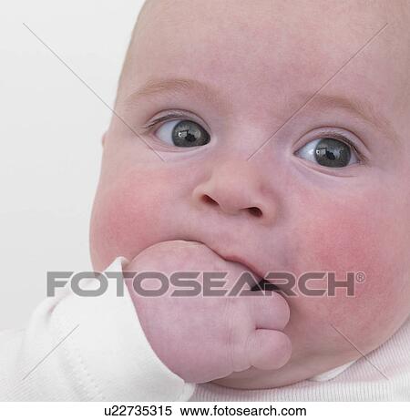 Stock Photography - Baby shoving hand into mouth, close-up. Fotosearch