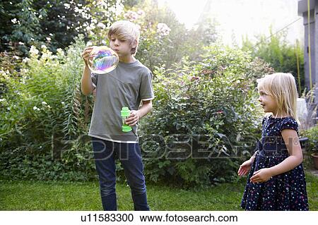 Stock Image - Boy and girl blowing bubbles. Fotosearch