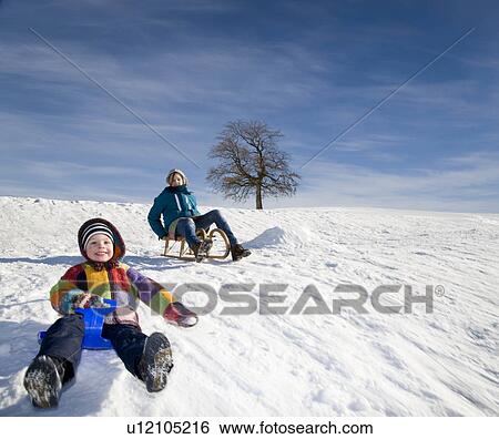 Boy and Girl riding a sledge in snow View Large Photo Image Stock Photograph - Boy and Girl riding a sledge in snow. Fotosearch