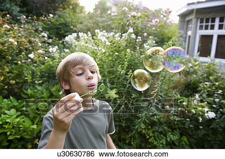 Stock Photograph - Boy blowing bubbles. Fotosearch