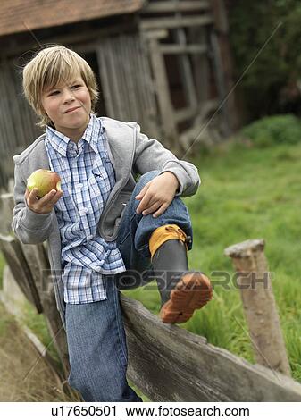 Boy eating apple, sitting on fence View Large Photo Image Stock Image - Boy eating apple, sitting on fence. Fotosearch