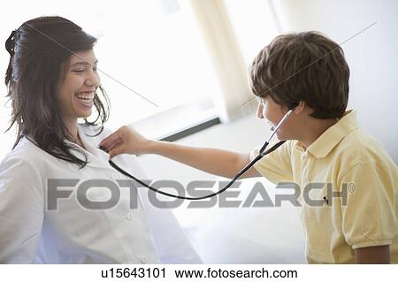 Stock Image - Boy listening to female Doctors heart. Fotosearch