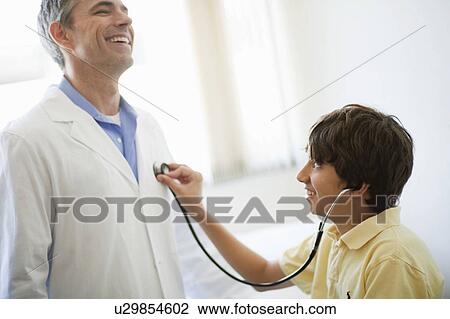 Boy listening to male Doctors heart View Large Photo Image Stock Image - Boy listening to male Doctors heart. Fotosearch