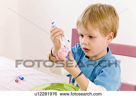 Stock Photograph - boy painting eggs for easter. Fotosearch