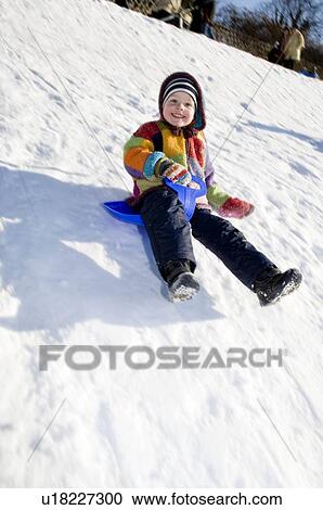 Stock Image - boy riding a sledge in snow. Fotosearch