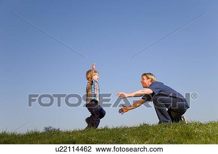 Stock Image - boy running into father's arms. Fotosearch