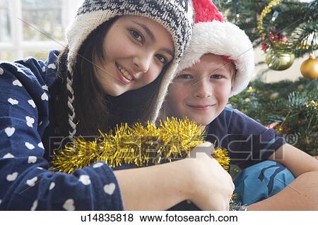 Brother and sister by Christmas tree View Large Photo Image Stock Photo - Brother and sister by Christmas tree. Fotosearch