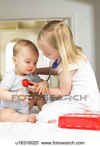 Stock Image - Brother and sister playing doctor. Fotosearch