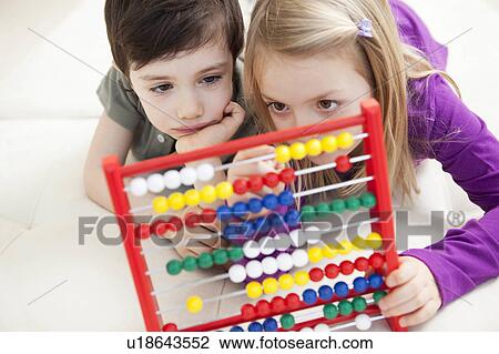 Stock Image - brother and sister playing with abacus. Fotosearch