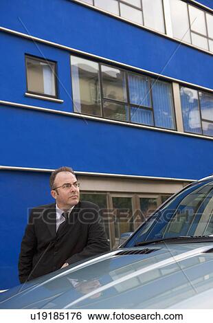 Businessman, chauffeur leaning on car View Large Photo Image Stock Photograph - Businessman, chauffeur leaning on car. Fotosearch